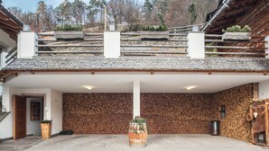 A covered outdoor area with a stone wall, wooden barrel planter, and a staircase leading to a roof terrace. - Holiday Apartment 'Riegelehof 1' with Balcony, Garden & Wi-Fi (Lajen)