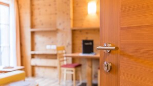 A wooden interior with a door, a table, and a chair. - Holiday Apartment 'Riegelehof 1' with Balcony, Garden & Wi-Fi (Lajen)