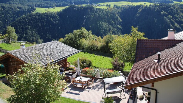 A cabin with a patio, surrounded by lush greenery and mountains. - Holiday Apartment 'Riegelehof 1' with Balcony, Garden & Wi-Fi (Lajen)