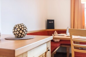 Een houten tafel met een bolvormig voorwerp, een rode, beklede bank en een zwart bord aan de muur.