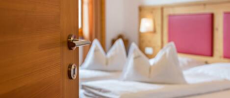 A hotel room with a wooden door, a bed with white bedding, and a pink headboard.