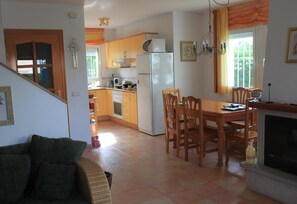 A kitchen with a dining table, chairs, a fireplace, and a staircase leading to another room. - 'Lovely Villa in Family Resort' with Pool, Garden & Wi-Fi (Miami Playa)