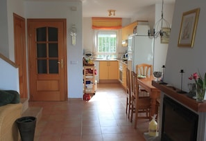 Una cocina con una mesa de comedor, sillas, un refrigerador y una ventana con cortinas.
