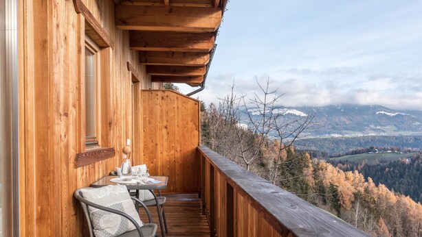 A wooden balcony with a table and chairs, overlooking a mountainous landscape. - Apartment 'Kehrerhof - Mountain' with Mountain View, Balcony & Wi-Fi (St. Lorenzen)