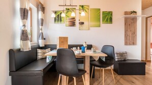 A modern dining area with a wooden table, black chairs, and a black leather sofa. - Apartment 'Kehrerhof - Mountain' with Mountain View, Balcony & Wi-Fi (St. Lorenzen)