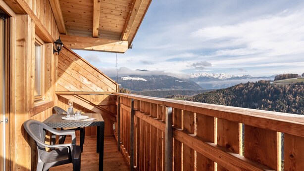 A wooden deck with a table and chairs, overlooking a mountainous landscape. - Apartment 'Kehrerhof - Panorama' with Mountain View, Balcony & Wi-Fi (St. Lorenzen)