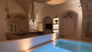 Quarto com piscina, paredes de pedra e luminária pendente.