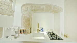 Casa de banho moderna com lavatório branco, máquina de café, chaleira e fogão a gás.