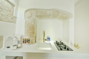 A modern bathroom with a white sink, a coffee maker, a tea kettle, and a gas stove.