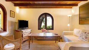 A cozy room with a television, wicker chairs, a sofa, a wooden table, and a window with an arched design. - Country House "Finca Los Dioses" in the Heart of Nature with Mountain View, Garden & Terrace (Mogán)
