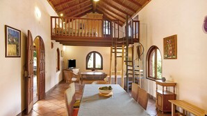 A spacious dining area with a high ceiling, wooden staircase, and a view of the outdoors. - Country House "Finca Los Dioses" in the Heart of Nature with Mountain View, Garden & Terrace (Mogán)