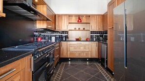 Een moderne keuken met houten kastjes, een roestvrijstalen koelkast en een zwart betegelde achterwand.