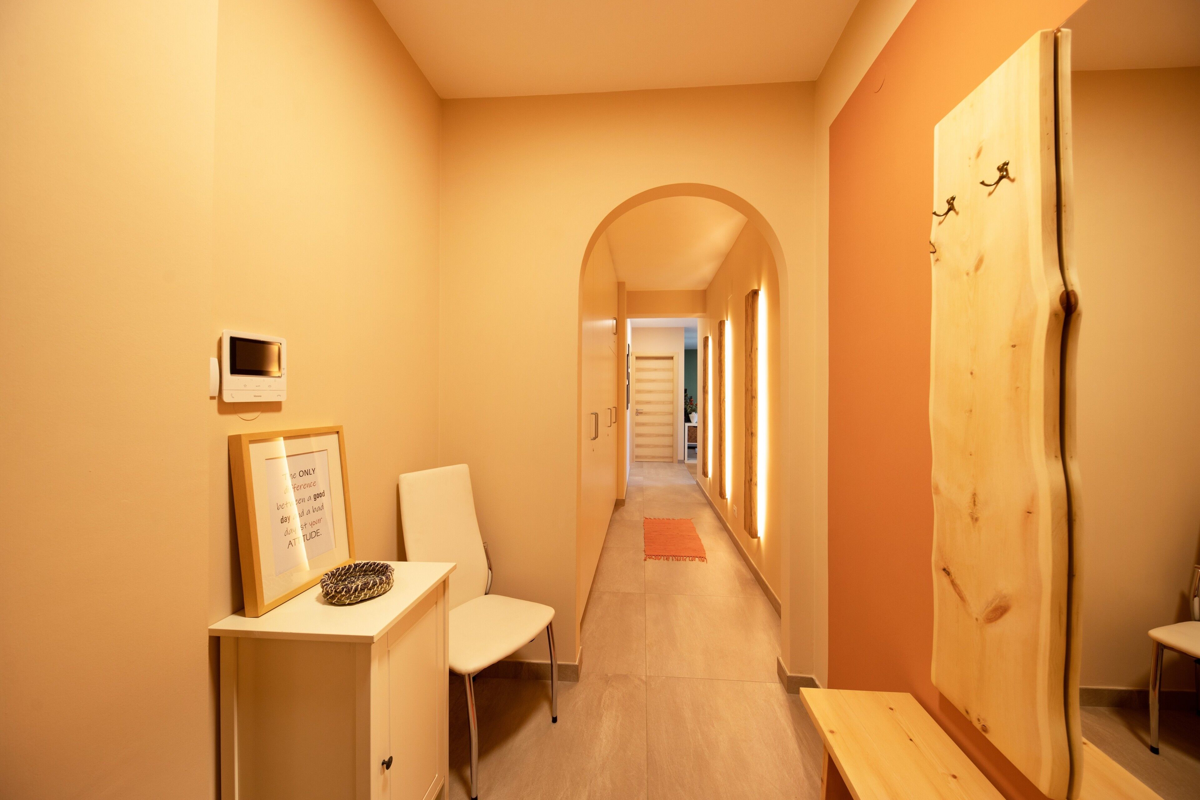 A hallway with a desk, chair, framed picture, and a wooden door.