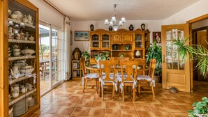 Un comedor con una mesa y sillas de madera, un aparador de vidrio con vajilla y un mueble de madera con objetos decorativos.