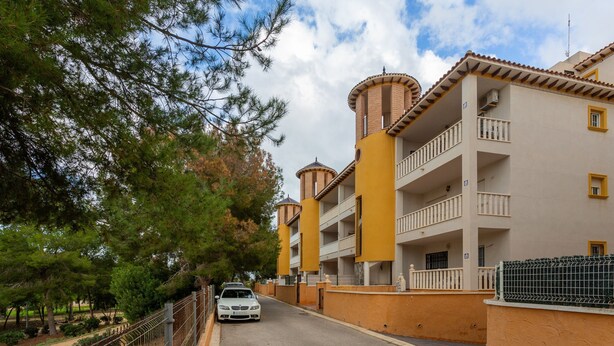 A multi-story building with balconies, a car parked in front, and trees in the background. - Vacation Apartment "Playa Golf 2" with Wi-Fi, Garden & Terrace (Cabo Roig)