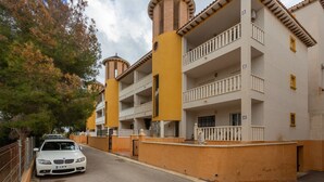 A multi-story building with balconies, a car parked in front, and a tree to the left. - Vacation Apartment "Playa Golf 2" with Wi-Fi, Garden & Terrace (Cabo Roig)
