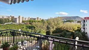 A balcony with a view of a residential area, a parking lot, and a hilly landscape. - Holiday Apartment 'Casa Isabea' with Sea View, 2 Balconies, Garden & Wi-Fi (Pozzuoli)