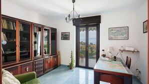 A room with a green sofa, a wooden cabinet with glass doors, a dining table, and a view through a glass door. - Holiday Apartment 'Casa Isabea' with Sea View, 2 Balconies, Garden & Wi-Fi (Pozzuoli)