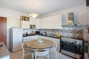 A kitchen with white cabinets, a microwave, a stove, and a dining table with chairs.