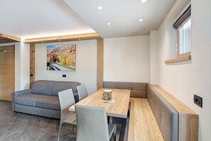 Un intérieur moderne avec un canapé, une table à manger, des chaises et un tableau au mur.
