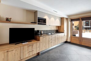 A modern kitchen with a flat-screen TV, built-in microwave, and wooden cabinets.