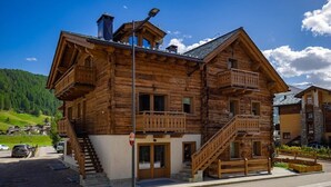 Un chalet en bois doté d’un balcon, d’un escalier et offrant une vue sur le paysage environnant.