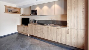 Une cuisine moderne avec des meubles en bois, un four à micro-ondes encastré et un évier en acier inoxydable.