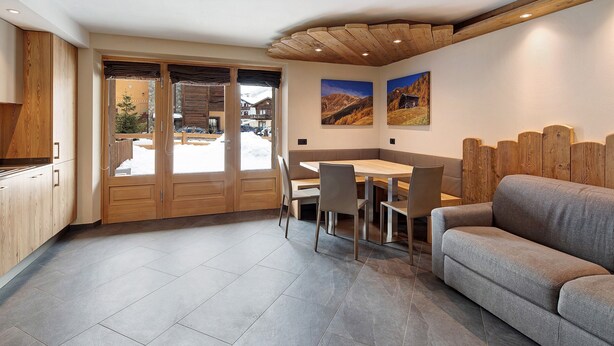 Une cuisine moderne avec des meubles en bois, un coin repas comprenant une table et des chaises, et un canapé.