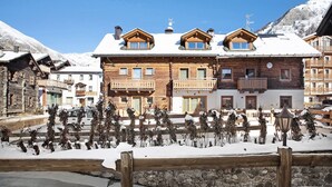Un bâtiment de style chalet en bois, doté de balcons, d’un mur en pierre et d’un sol recouvert de neige.