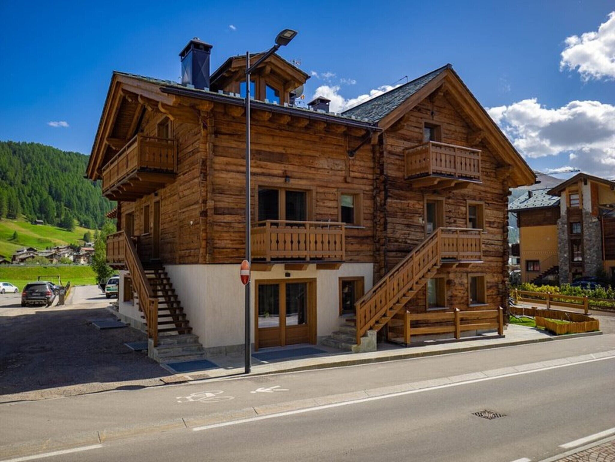 A wooden chalet with a balcony, a staircase, and a view of the surrounding landscape.