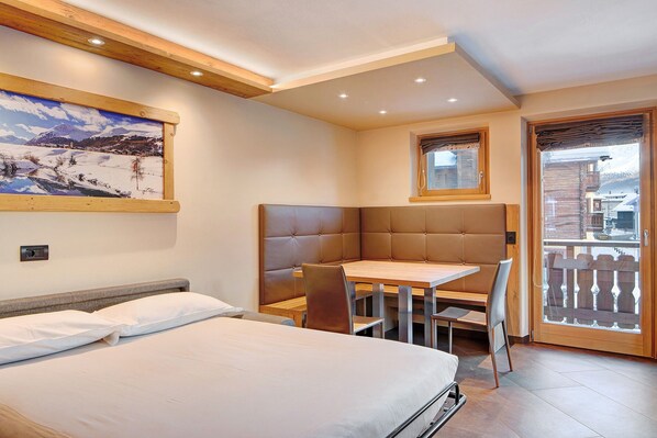 Une chambre d’hôtel avec un lit, une table à manger et un balcon.
