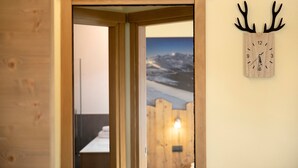 A wooden door leading to a room with a wooden wall clock and a poster of a snowy landscape. - Night Apartment – Rasia Residence Relax with Balcony and Wellness Area (Livigno)