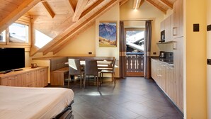A cozy attic bedroom with a bed, a desk, and a dining area. - Night Apartment – Rasia Residence Relax with Balcony and Wellness Area (Livigno)