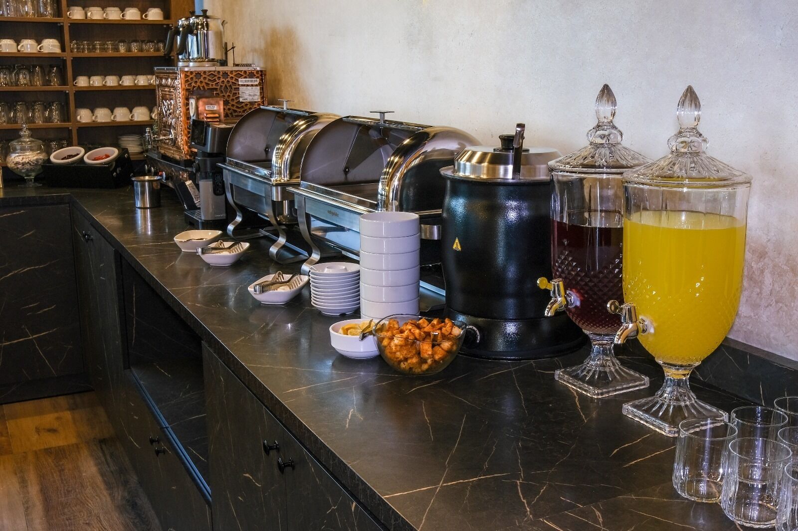 A buffet setup with various food items, a coffee machine, and a beverage dispenser.