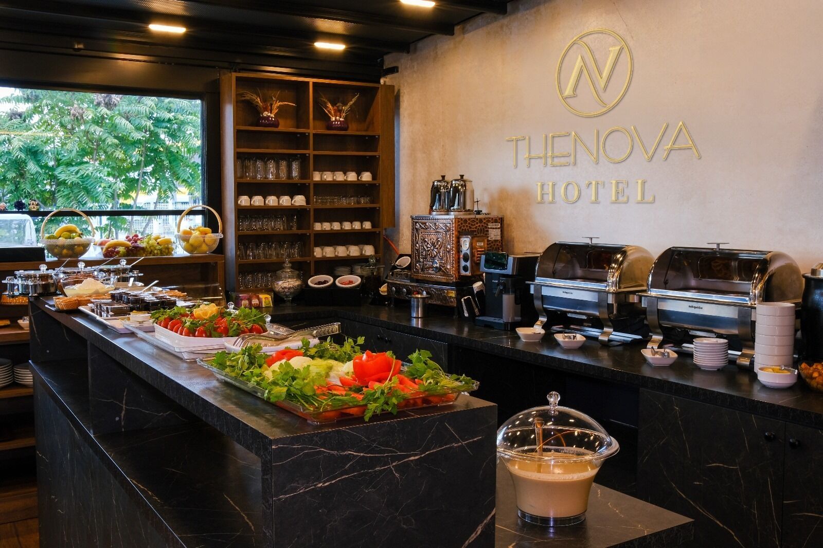 A hotel breakfast buffet with a variety of fruits, vegetables, and beverages, and a coffee machine.