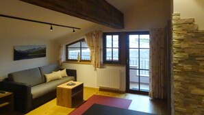 A living room with a sofa, a coffee table, a radiator, and a window with curtains.