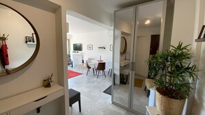 Ein modernes Wohnzimmer mit einem großen Spiegel, einem Essbereich mit Tisch und Stühlen sowie einer Kübelpflanze.