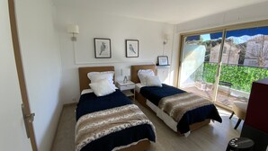 Ein Hotelzimmer mit zwei Betten, einem Balkon mit Blick und gerahmten Kunstwerken an der Wand.