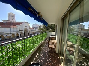 A balcony with a view of historic buildings, a table with chairs, and a blue awning. - Cannes basse californie 5 minutes Croisette (Cannes)