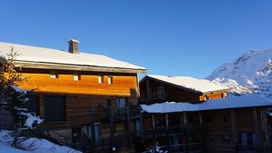 Eine Holzlodge mit mehreren Balkonen und einem schneebedeckten Berg im Hintergrund.