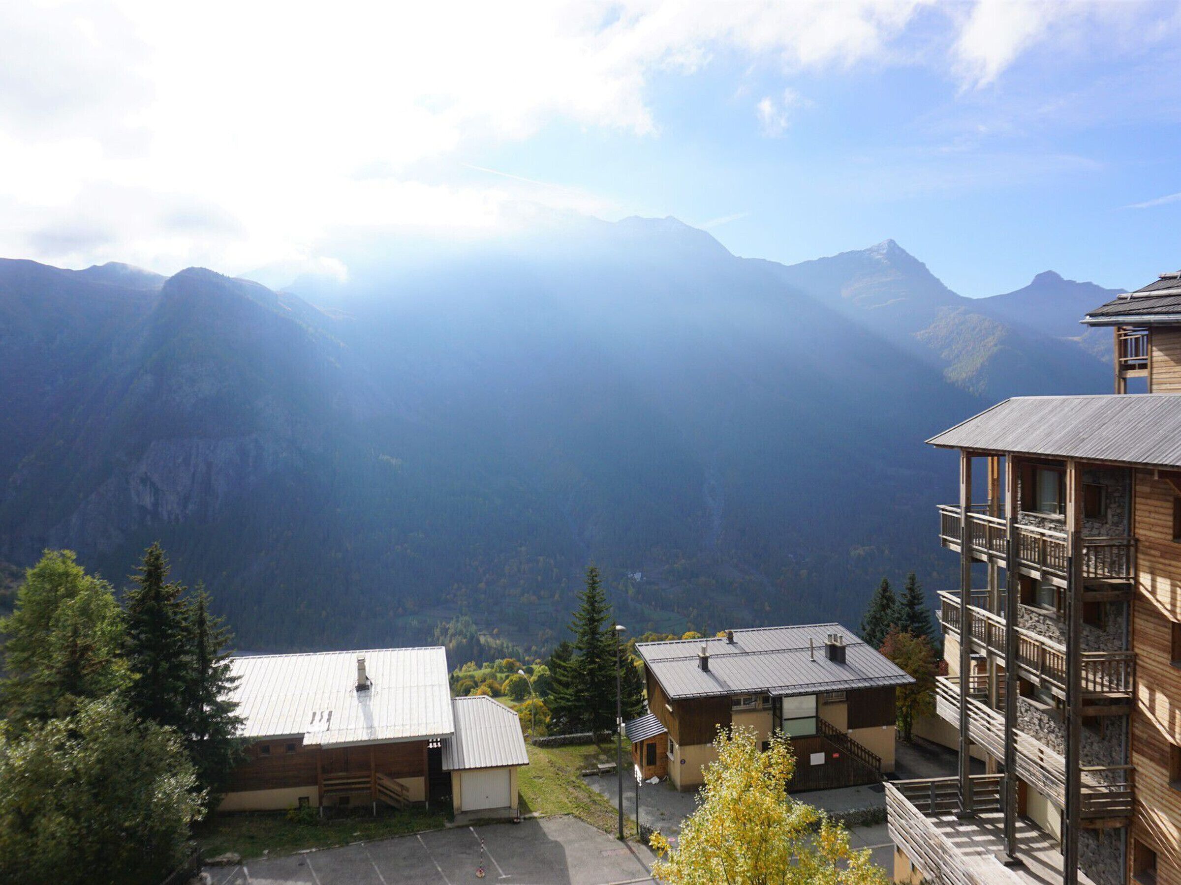Eine Berglodge mit Holzfassade, einem kleinen Anbau und einem Balkon mit Blick über ein Tal.
