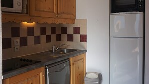 Eine Küche mit Holzausstattung, einer Mikrowelle, einem Toasterofen, einem Geschirrspüler und einer gefliesten Spritzschutzwand.