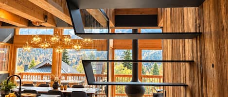 A modern interior with wooden paneling, a kitchen area, and a dining space with a view of mountains.
