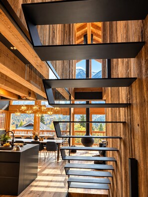 A modern interior with wooden paneling, a kitchen area, and a dining space with a view of mountains.