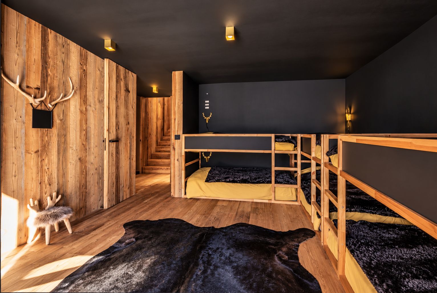A room with wooden bunk beds, a fur rug, and antlers on the wall.
