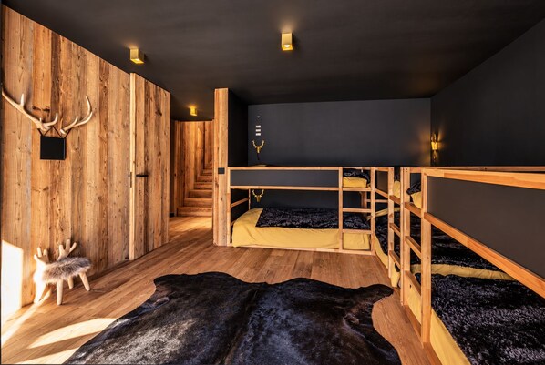 Quarto com beliches de madeira, tapete de pele e chifres na parede.