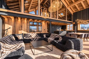 A modern interior with a sectional sofa, a dining table, and a kitchen area.