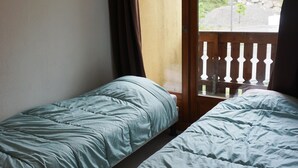 Ein Zimmer mit zwei Einzelbetten, einem hölzernen Balkon mit weißer Brüstung und einem gerahmten Bild an der Wand.