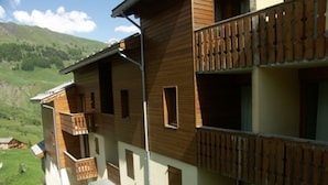 Ein mehrstöckiges Gebäude mit Holzbalkonen und Blick auf ein grünes Tal.