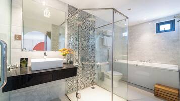A modern bathroom with a glass-enclosed shower, a white sink, and a large bathtub.